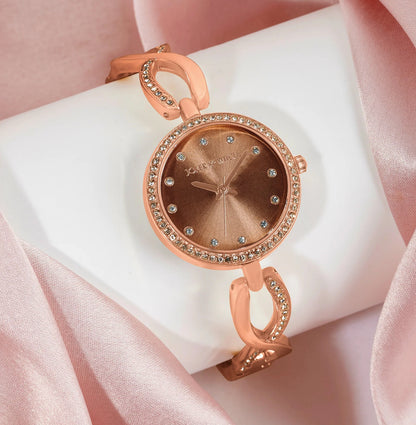 NOELLA TAUPE TWISTED METALLIC STRAP WATCH WITH RHINESTONE DETAILS.